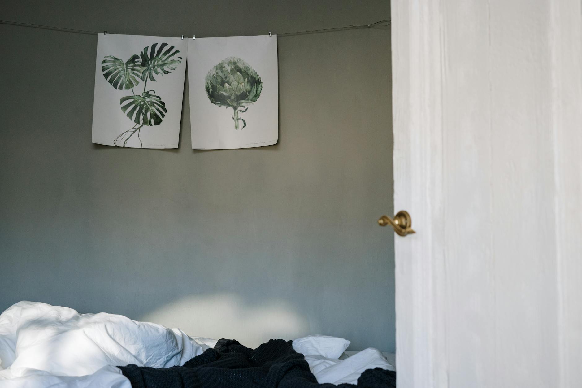 Bedroom with botanical art on the wall and soft linen bedding in warm morning light