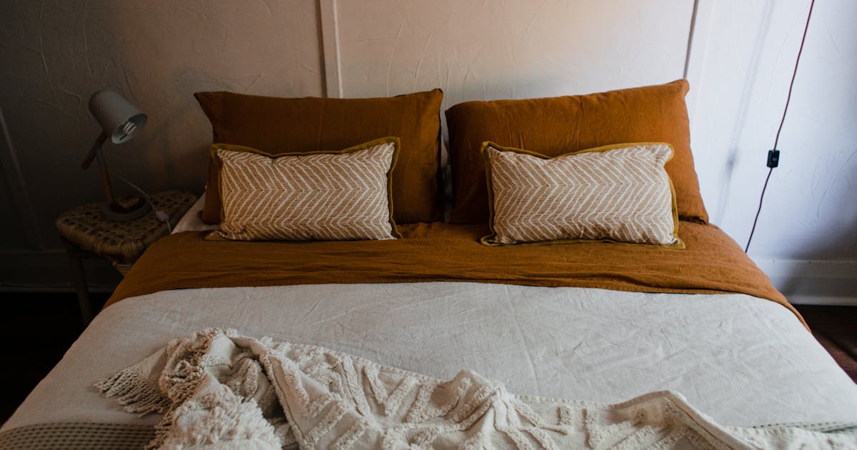 Inviting bedroom with warm tones, featuring a neatly arranged bed and soft lighting