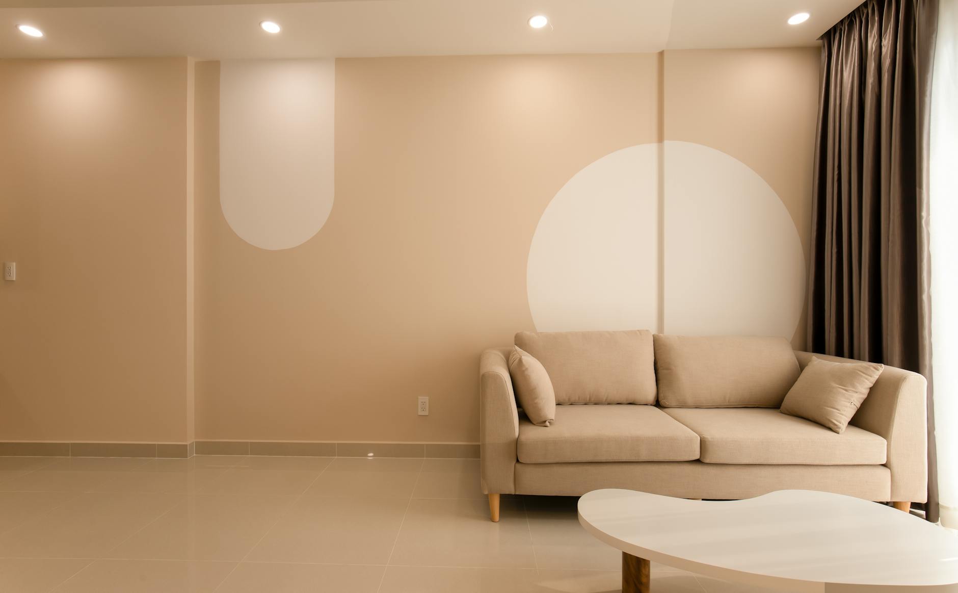 A cozy minimalist living room with a beige sofa, neutral tones, and warm afternoon light