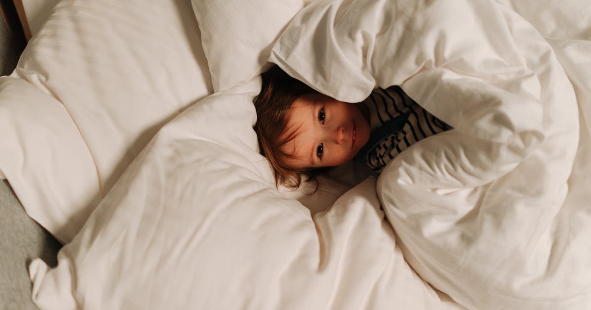 Little child snuggled warmly in soft blankets, enjoying bedtime comfort.