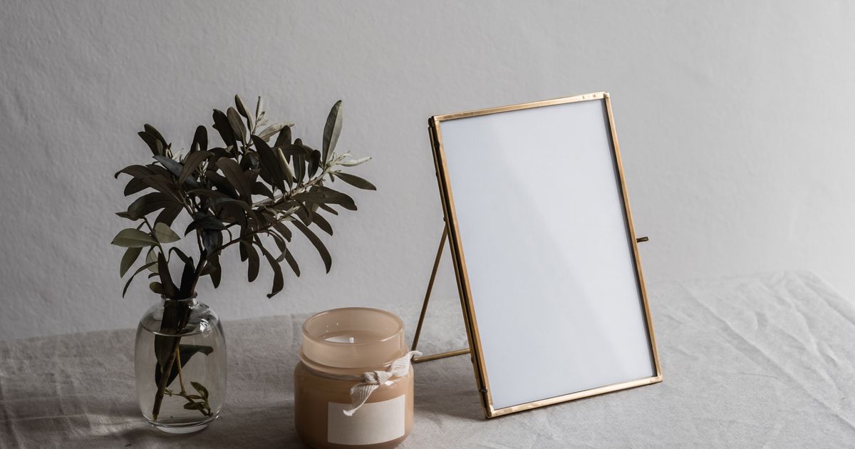 Elegant still life with a framed mockup, candle, and small plant on a textured surface.