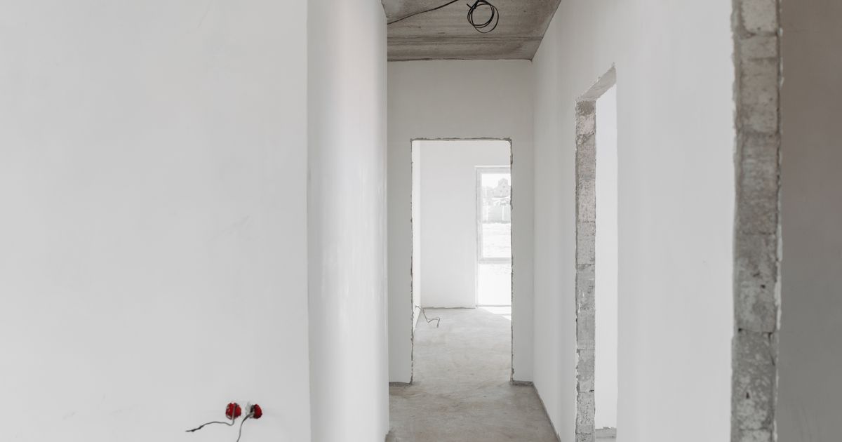 A minimalist view of an unfinished building interior with white walls and door frames.