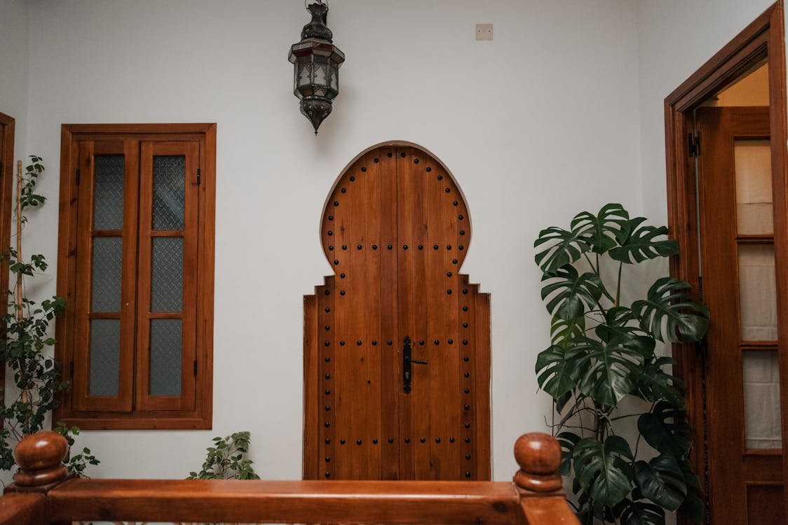 A Mediterranean-style entrance with a warm wooden arched door and terracotta accents