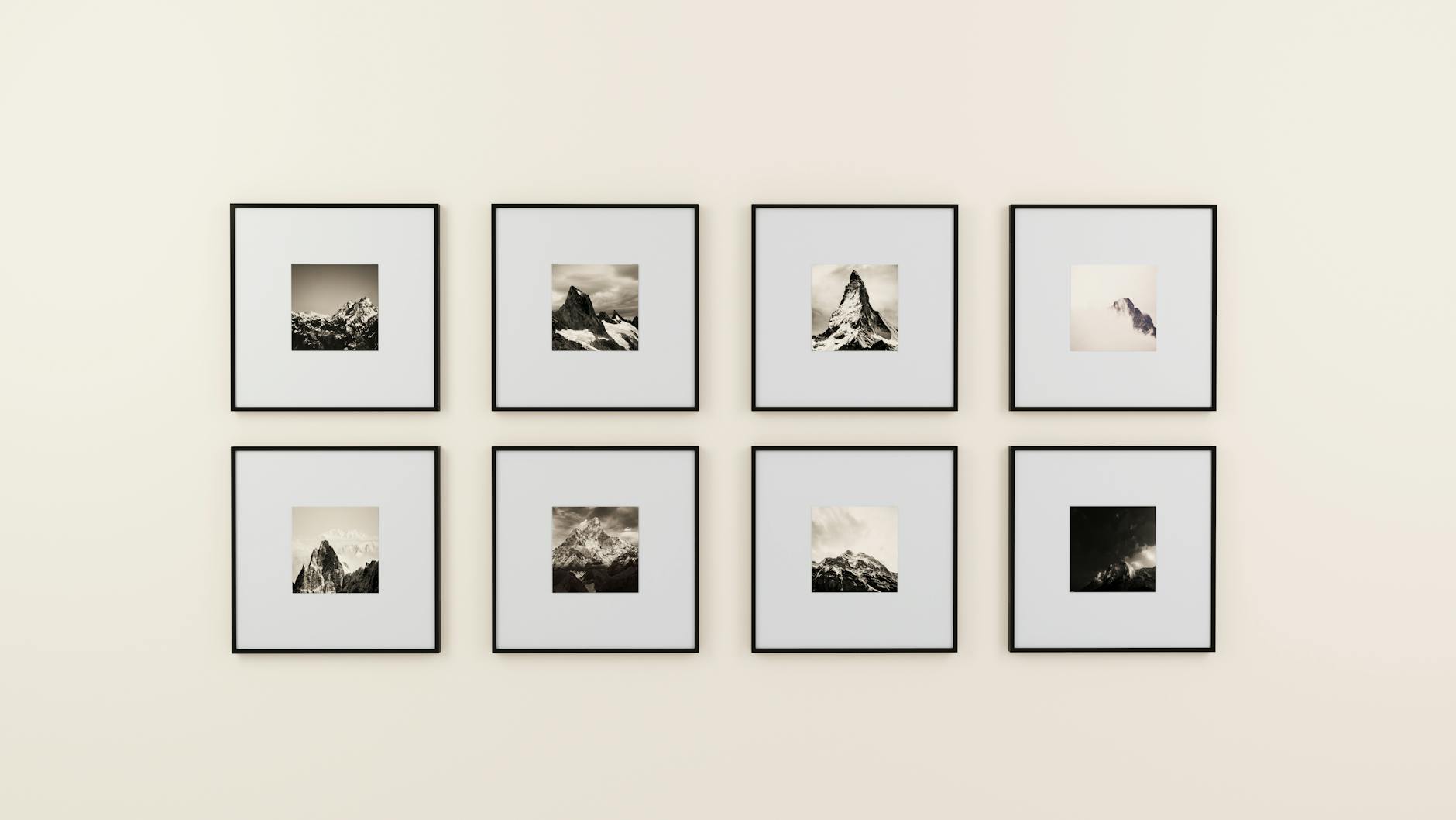 A minimalist display of framed photography prints on a plain wall in warm light