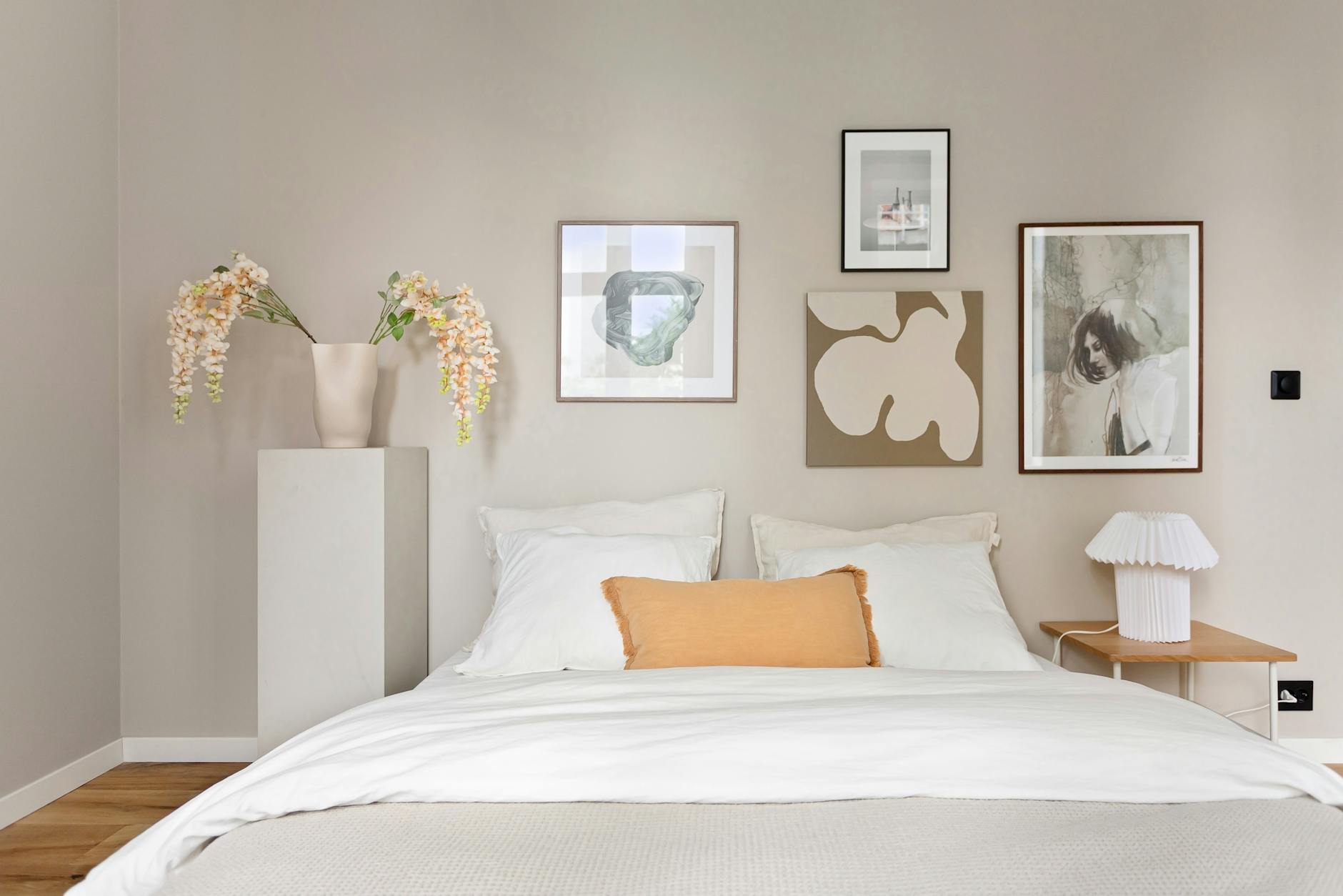 Elegant minimalist bedroom with framed art print on the wall in neutral tones and warm morning light.