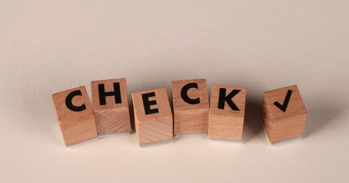 Wooden blocks aligned to spell 'CHECK' with a checkmark symbol on a neutral background.