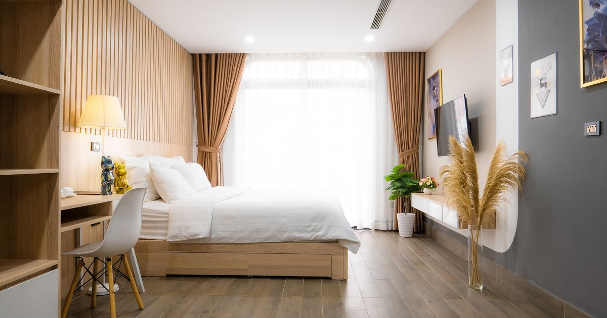 A modern minimalist bedroom with natural light, featuring cozy decor and wooden accents.