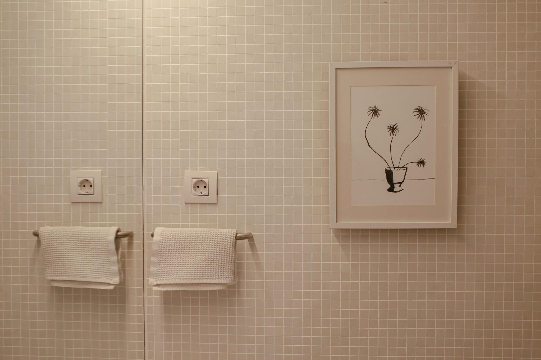 Elegant bathroom with framed art and textured towels on tiled wall