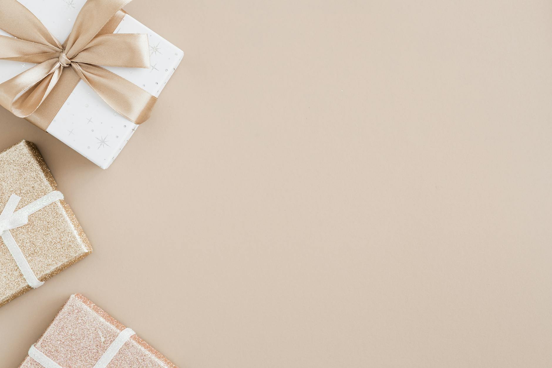 Elegant minimal gift boxes with ribbons on a beige background, warm and neutral tones