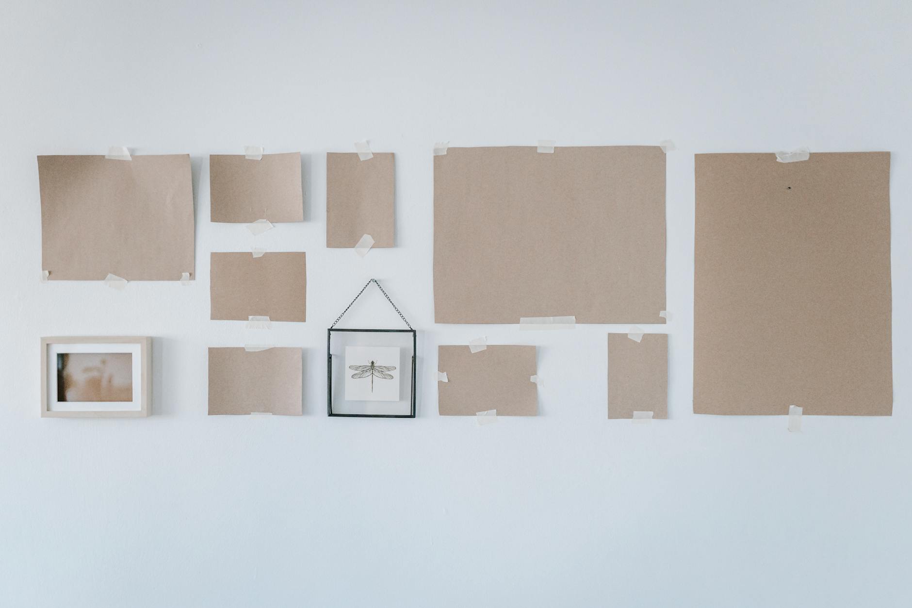 Kraft paper templates taped to a white wall showing gallery wall layout planning in a minimalist home