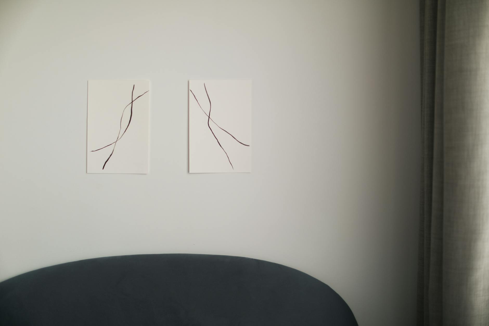 Abstract linear wall art in a minimalist modern living room with soft lighting and warm neutral tones.