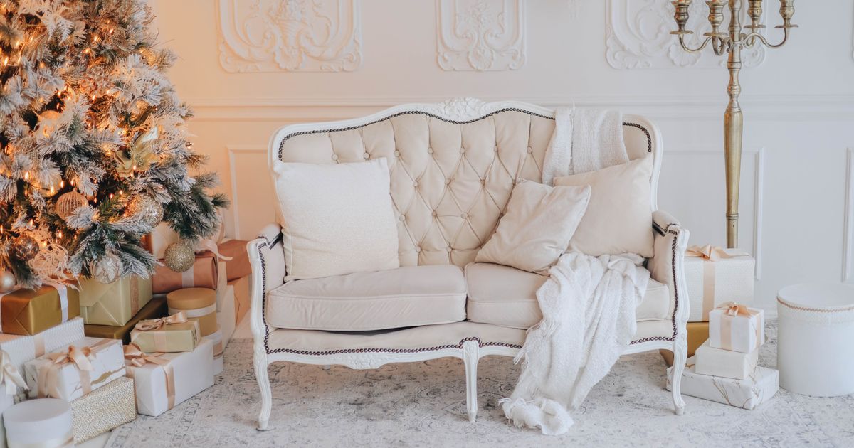 Warm, elegant living room decorated for Christmas with tree, gifts, and cozy sofa.