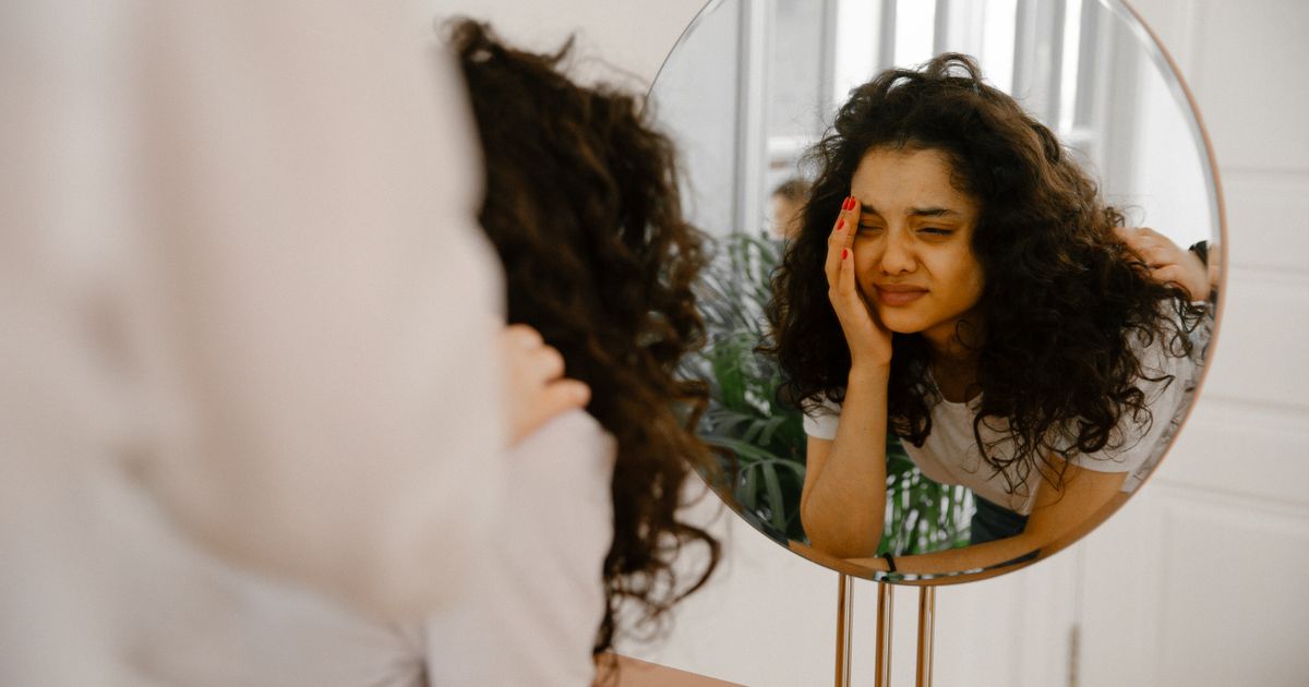 A young woman gazes into a mirror, reflecting her inner emotions and self doubt.