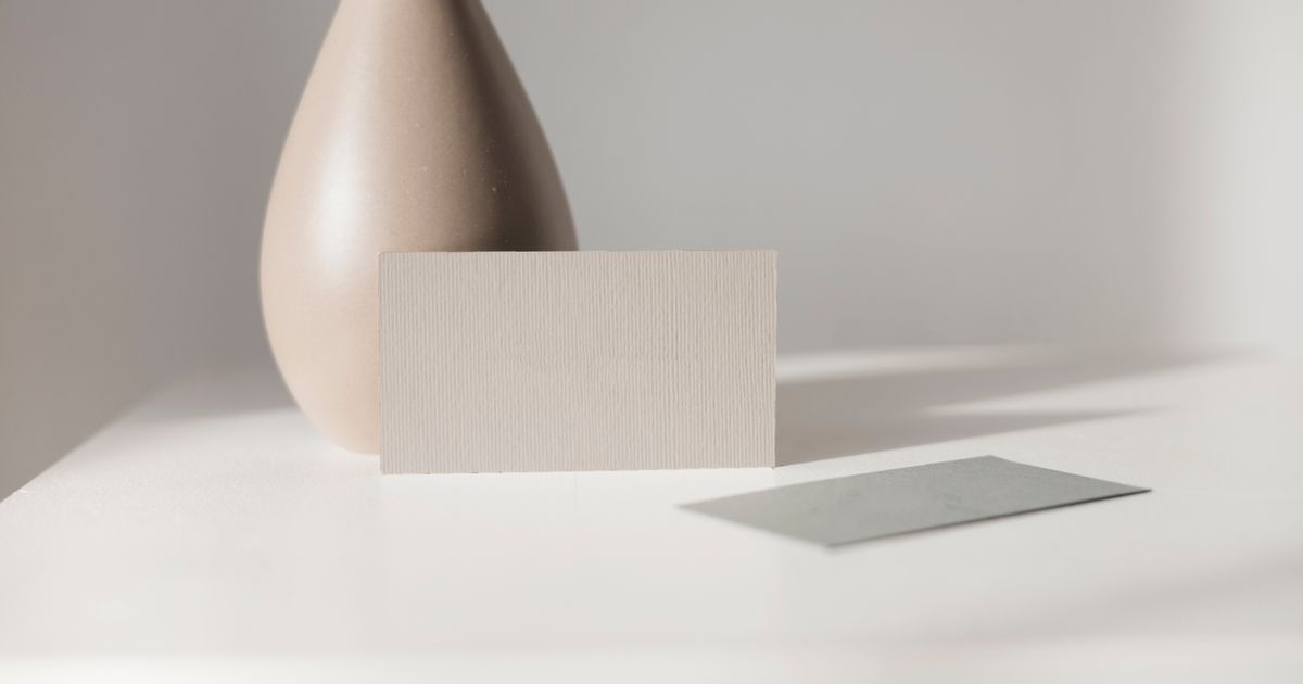 Elegant minimalist mockup featuring a blank card and ceramic vase on a white table. Perfect for branding or design.