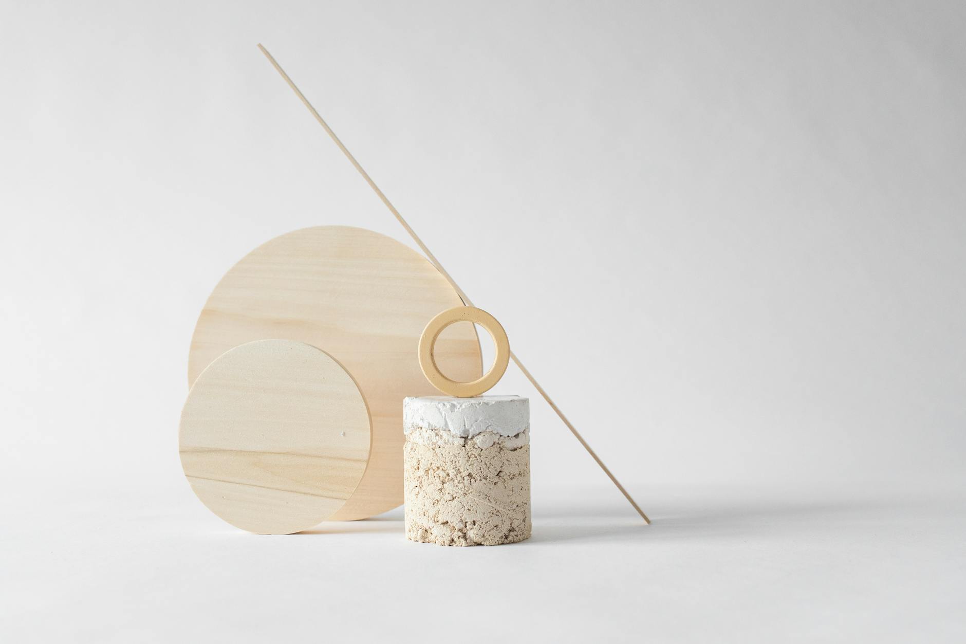 Minimalist composition with wooden circles and stone elements on a light neutral background