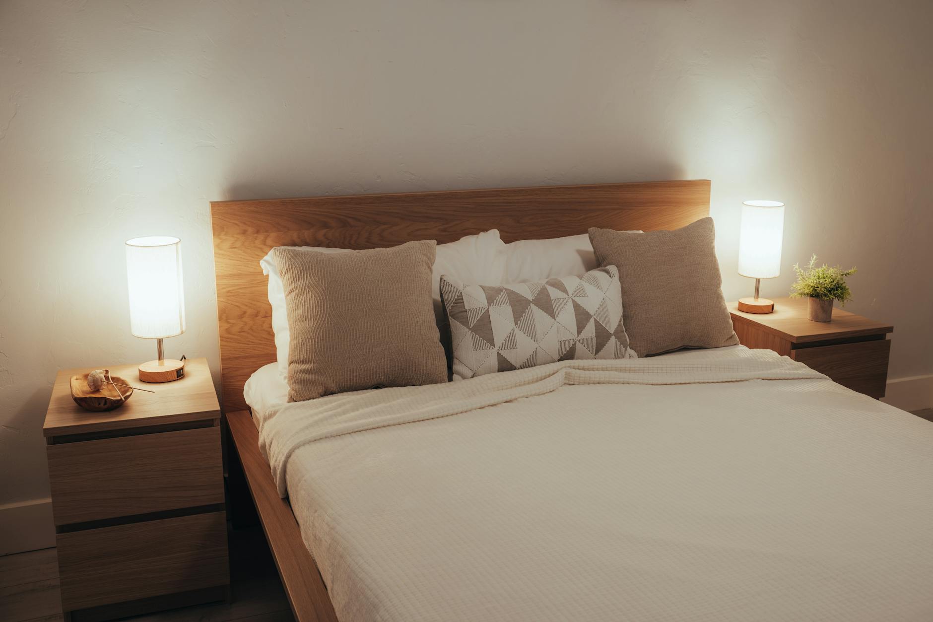 Minimalist bedroom with soft lighting, modern furniture, and cozy neutral bedding